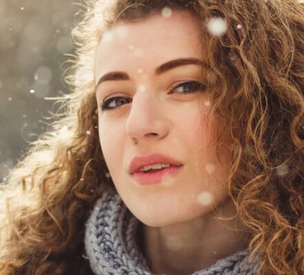 Primo piano di ragazza con capelli ricci sotto la neve